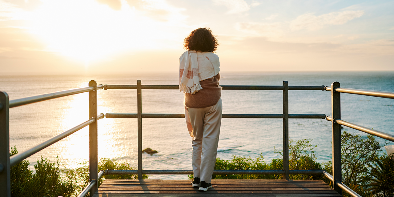 Woman standing on pier overlooking a body of water.