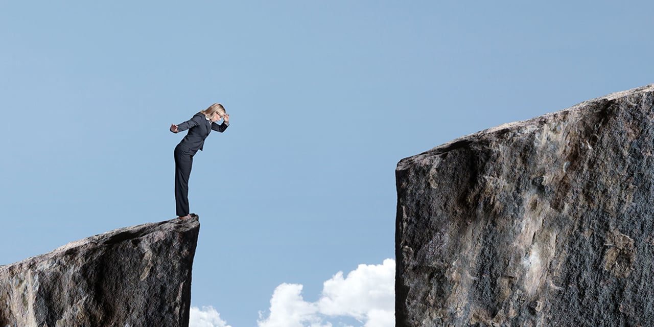 Person standing on a cliff looking into the opening below.